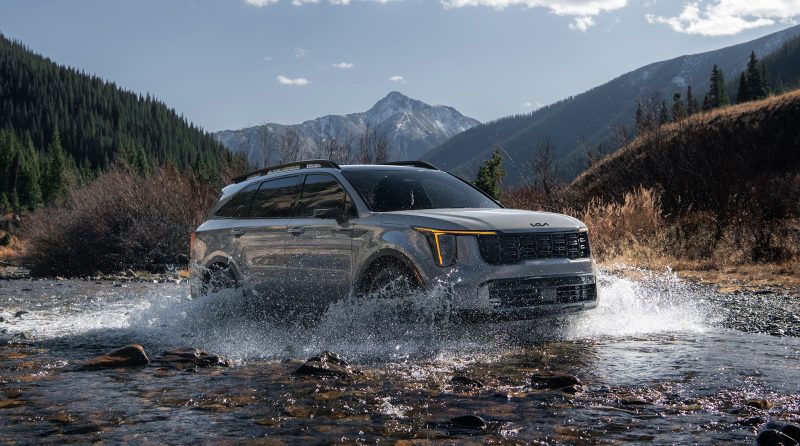 Gray Kia Sorento X-Pro driving through a river in the mountains.